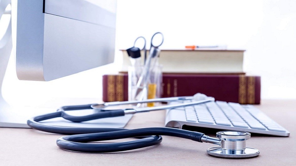 Stethoscope sitting on a desk next to a keyboard